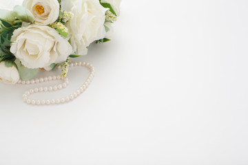 White background with a wedding bouquet, pearl beads and a Cup of coffee with milk, with copy space. Concept backgrounds for wedding texts or romantic texts.