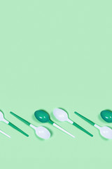 Plastic spoons on mint green background. Flat lay, top view copy space.