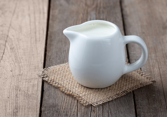 Fototapeta na wymiar White jug with milk on a wooden rustic background