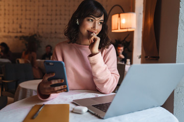 Cheerful woman indoors in cafe using laptop