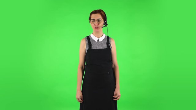 Funny girl in round glasses with headset helping with customer service and worry. Green screen