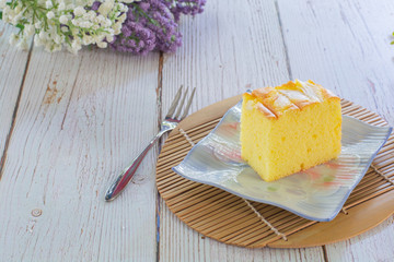 Piece of vanilla chiffon coconut cake on square plate on wooden table. Delicious small bakery for...