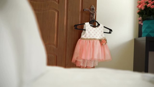 peach dress hanging on the door for baby girl