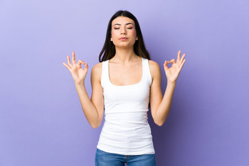 Young brunette woman over isolated purple background in zen pose