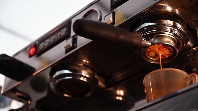 Close up of Espresso machine making an espresso with a "naked" portafilter, directs high-pressure hot water through the coffee puck. The espresso machine is a tool that serves to prepare fresh coffee.