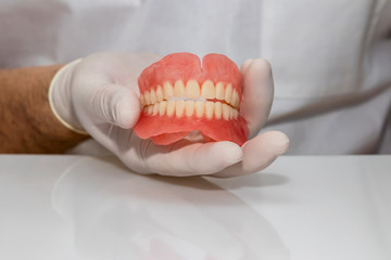 Fototapeta na wymiar False teeth prosthesis. Doctor Dentist. A dental technician holds a false jaw in his hand.