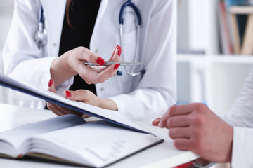 Fototapeta premium Female doctor hand hold silver pen and showing pad. Physical agreement form signature disease prevention ward round reception consent contract sign prescribe remedy healthy lifestyle concept