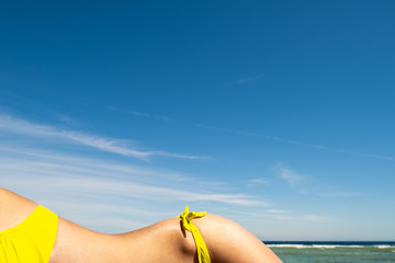 Fototapeta premium Close up of young woman hip and shoulder laying on beach chair at sea shore sunbathing.