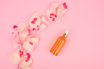 Organic cosmetic with rose oil on pink background. Top view.