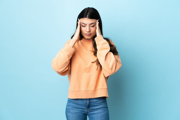 Young brunette girl over isolated blue background with headache