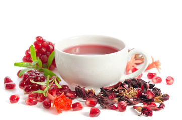 Parts of a pomegranate with pomegranate seeds and leaves, flowers, dry tea of carcade and full cup of tea isolated on white background