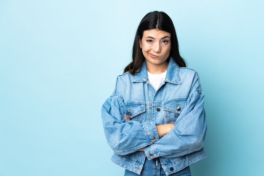 Young brunette girl over isolated blue background feeling upset