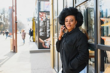 cheerful african woman using smart phone outdoors