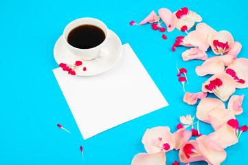 Cup of coffee with flowers decor on light blue table. Love and romance concept.