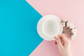 Empty coffee cup and flower on beautiful pink and bright blue pastel background.