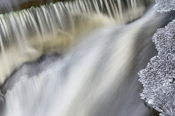 Fototapeta na wymiar Bond Falls cascade captured with motion blur and framed by ice, Michigan's Upper Peninsula, USA