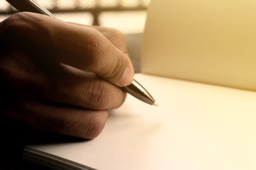 Hand holding a pen for sign business document notebook