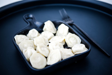 Raw fresh dumplings with meat or vegetarian dumplings with soy and spinach on black background. Food and cooking in the kitchen concept. Place for text. Copy space