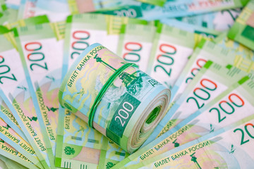 Roll of russian 200 rubles banknotes at paper money background.