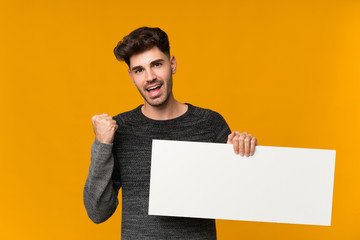 Young man over isolated background holding an empty white placard for insert a concept