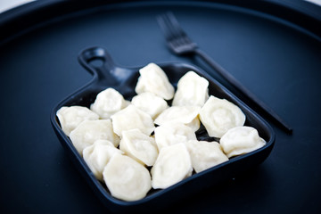 Raw fresh dumplings with meat or vegetarian dumplings with soy and spinach on black background. Food and cooking in the kitchen concept. Place for text. Copy space