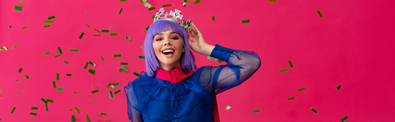 panoramic shot of excited attractive pop art girl in purple wig and crown on party with confetti, isolated on pink