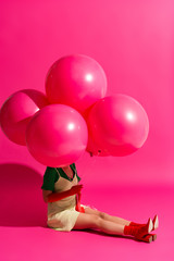 Fototapeta na wymiar beautiful young woman holding balloons on pink