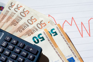 Business crisis and economic crisis concept image. Pile of Euro banknotes with calculator on analysis and data sheets.