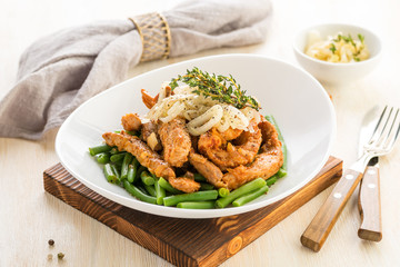 Roasted beef or pork meat slices with a side dish of green vegetables.