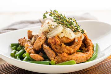 Roasted beef or pork meat slices with a side dish of green vegetables.