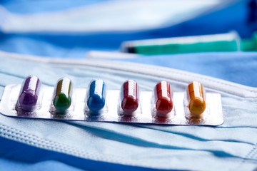 Pharmaceutical medicine tablets, pills, capsules and medical mask on blue background. Medicine concept. Coronavirus