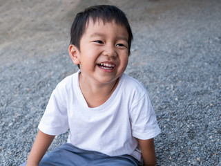 Asian cute little child boy laughing smiling, seeing whitening teeth. Happy Kid in white shirt enjoy in funny shot in relaxing day. © Namphueng