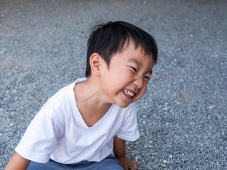 Asian cute little child boy extreme laughing, seeing whitening teeth. Happy Kid in white shirt enjoy in funny shot in relaxing day.