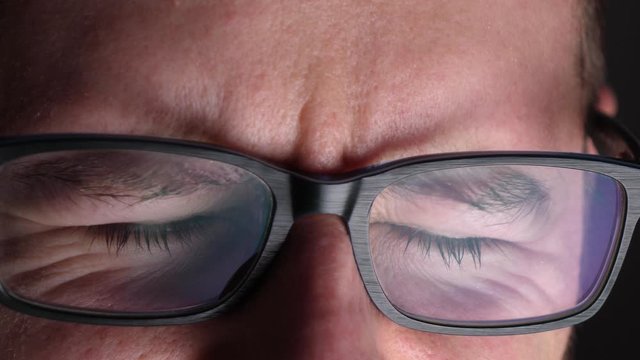 Digital screen flashes on a working hacker in the dark, closeup 