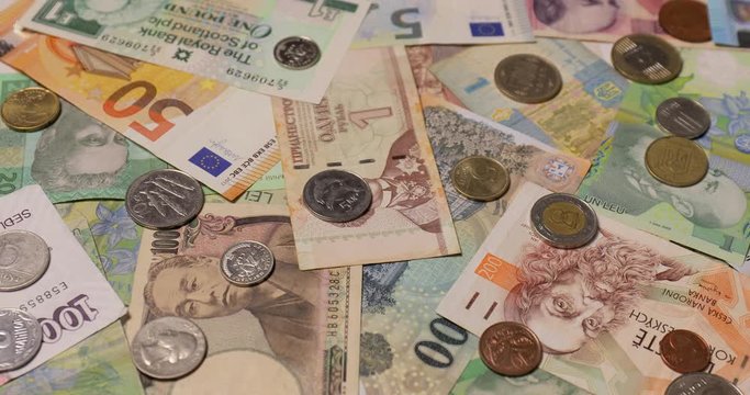 Currencies from around the world, collage of banknotes and coins, panning camera motion