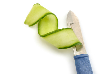 Peeler knife and cucumber shaving on white