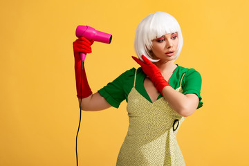 pop art girl in white wig using hair dryer, isolated on yellow