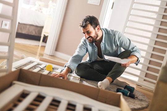 Man Assembling A Baby Crib.