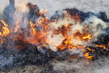 Bonfire on a snowy surface. Burning straw, bright flames and smoke of the fire.