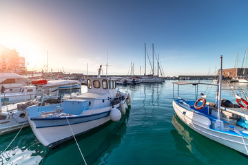 Fototapeta na wymiar Panoramic view of beautiful sunset in Koules Fortress (Rocca a Mare), Crete island. Yachts reflecting in the mirror of water near Venetian old harbor in Heraklion city. Amazing destination in Greece
