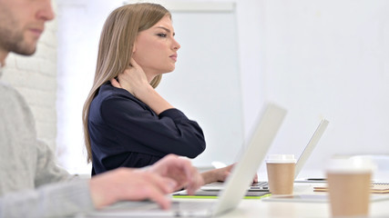 Creative Woman working on Laptop and having Neck Pain in Office