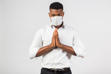 Afro-American man of mixed race, in a white shirt and medical mask, hands in a gesture of prayer,...