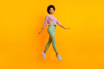 Fototapeta na wymiar Full length photo of cheerful dreamy afro american girl jump enjoy fall spring free time wear casual style clothes isolated over shine color background