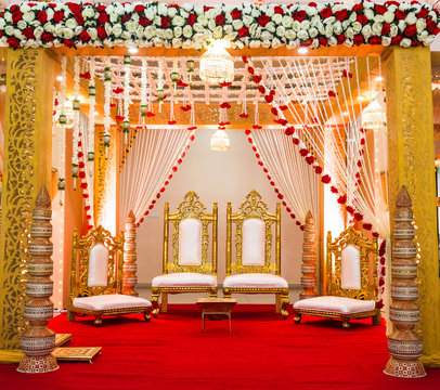 India wedding stage red and gold decor with gold chairs and flowers and red carpet for Mandap Stage 