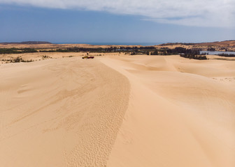 Aerial view of brown winding sand dunes with four-wheel car
