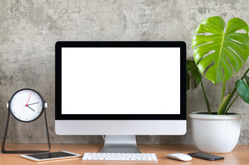 Blank screen of All in one computer, keyboard, mouse,  tablet, smart phone, monstera plant pot and clock  on wooden table - obrazy, fototapety, plakaty