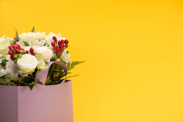 spring fresh bouquet of flowers in violet paper bag isolated on yellow
