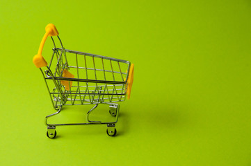 Trolley for shopping on a green background. Supermarket food price concept, holiday discounts