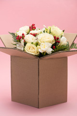 bouquet of flowers in carton box on pink background