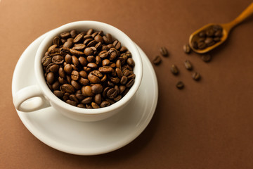 Coffee cup with roasted beans on brown table